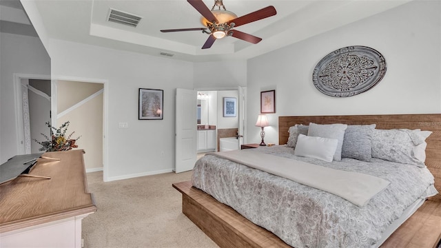 bedroom featuring a tray ceiling, visible vents, light carpet, and baseboards