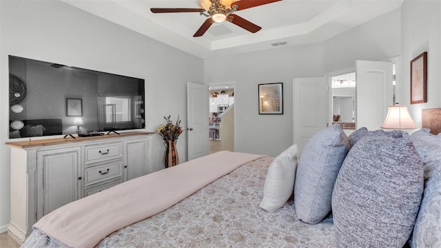 bedroom with a tray ceiling, a high ceiling, visible vents, and a ceiling fan