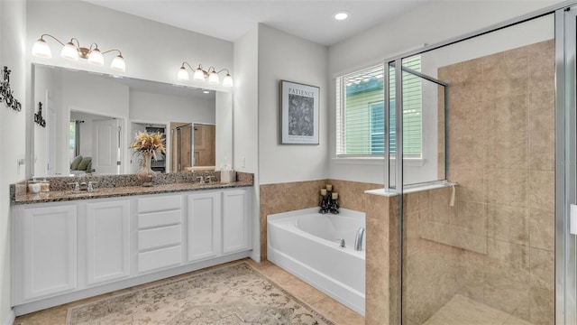 bathroom featuring double vanity, a bath, tile patterned floors, a shower stall, and a sink