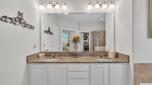 bathroom with double vanity, a stall shower, and a sink