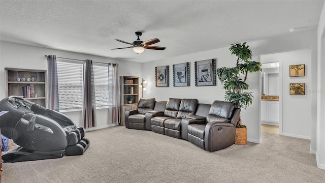 living room featuring ceiling fan, a textured ceiling, baseboards, and light colored carpet