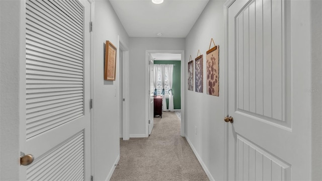 hall featuring light carpet and baseboards