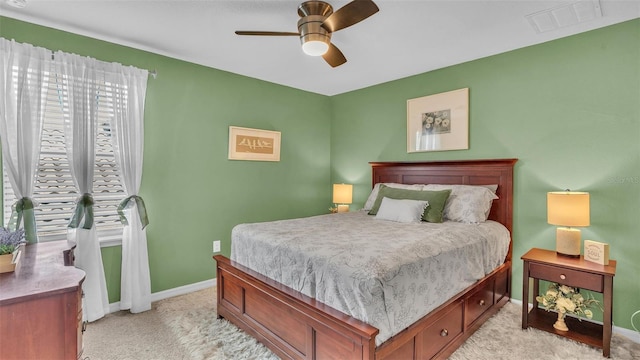 bedroom with light carpet, ceiling fan, visible vents, and baseboards