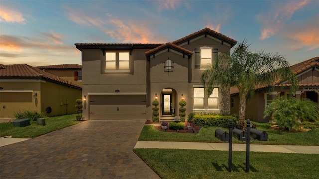 mediterranean / spanish-style home with decorative driveway, a lawn, an attached garage, and stucco siding