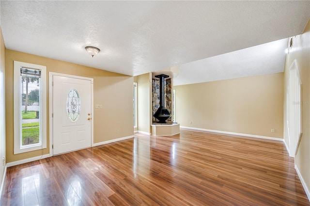 foyer entrance with hardwood / wood-style floors, a textured ceiling, and a wood stove