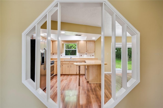 kitchen featuring appliances with stainless steel finishes, sink, light brown cabinets, a textured ceiling, and light hardwood / wood-style flooring