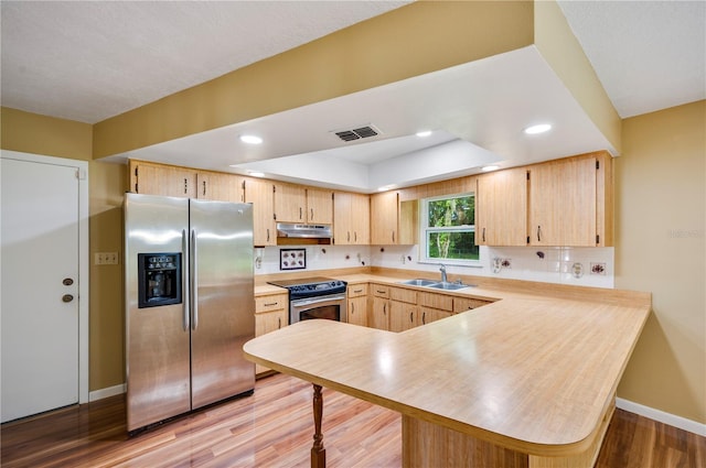 kitchen featuring stainless steel appliances, light brown cabinetry, kitchen peninsula, and sink