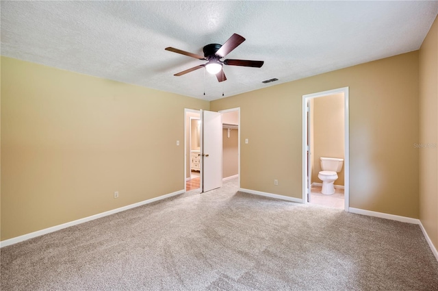 unfurnished bedroom featuring carpet flooring, a textured ceiling, ceiling fan, and ensuite bathroom