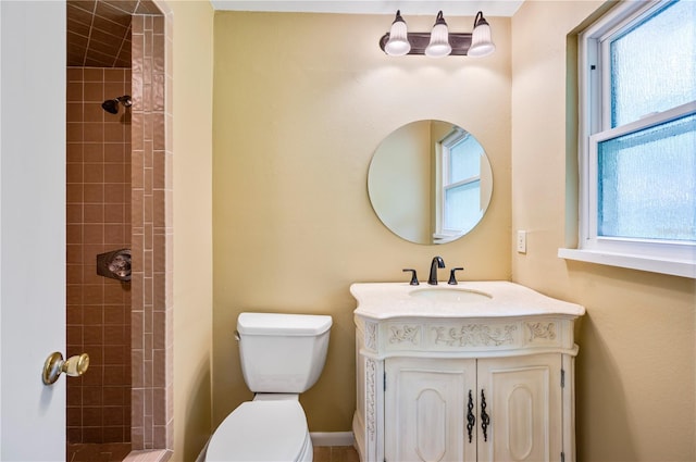 bathroom featuring vanity, plenty of natural light, toilet, and tiled shower