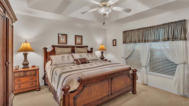 carpeted bedroom featuring a raised ceiling and ceiling fan