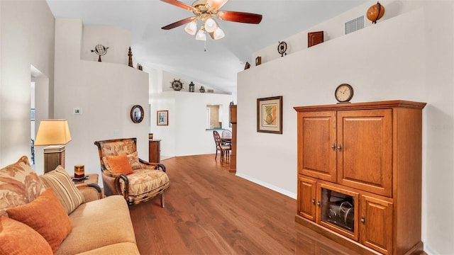 living room with ceiling fan, vaulted ceiling, and dark hardwood / wood-style flooring