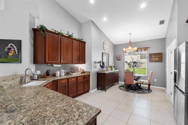 kitchen with kitchen peninsula, stainless steel fridge, sink, light tile patterned floors, and a chandelier