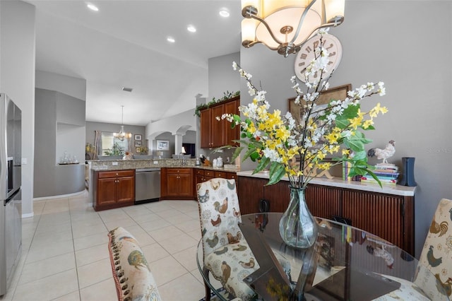 kitchen with a notable chandelier, appliances with stainless steel finishes, decorative light fixtures, kitchen peninsula, and lofted ceiling