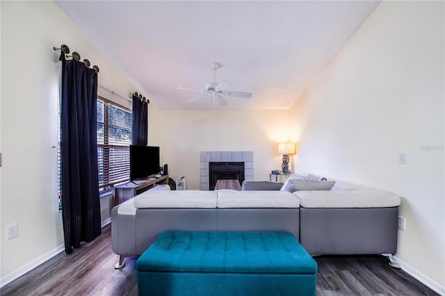 living room featuring ceiling fan, dark hardwood / wood-style flooring, and a tiled fireplace