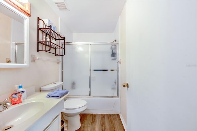 full bathroom with bath / shower combo with glass door, wood-type flooring, vanity, and toilet