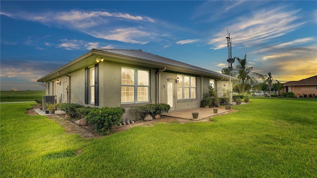 property exterior at dusk with cooling unit and a lawn