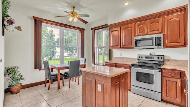 7884 N Lake Buffum Shores Rd, Fort Meade, FL 33841 - kitchen featuring appliances with stainless steel finishes, light stone counters, light tile patterned floors, a center island, and ceiling fan