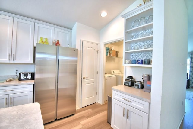 kitchen featuring white cabinetry, stainless steel fridge, light hardwood / wood-style floors, and washer and dryer