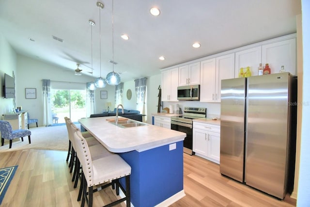 kitchen with white cabinetry, sink, hanging light fixtures, stainless steel appliances, and a center island with sink