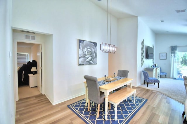 dining space with an inviting chandelier, hardwood / wood-style floors, and high vaulted ceiling