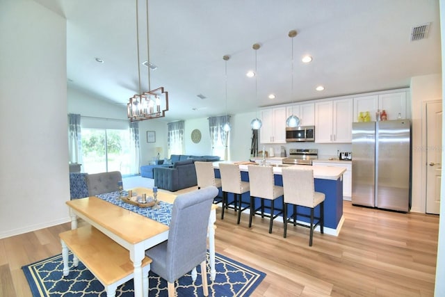 dining area with vaulted ceiling and light hardwood / wood-style floors