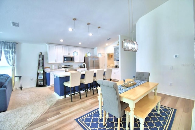 dining space featuring an inviting chandelier, sink, and light hardwood / wood-style floors