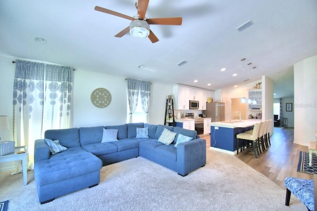 living room featuring ceiling fan, lofted ceiling, and light hardwood / wood-style floors