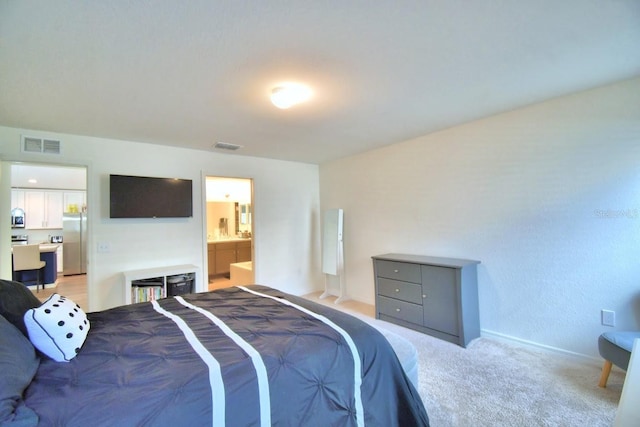 carpeted bedroom featuring stainless steel refrigerator and ensuite bathroom