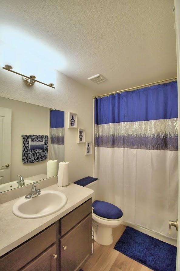 bathroom featuring vanity, hardwood / wood-style flooring, toilet, and a textured ceiling