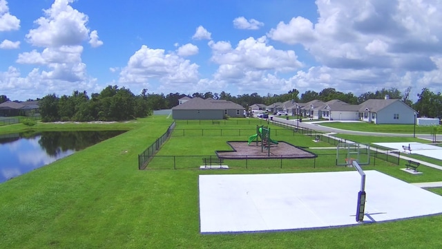 view of property's community with a lawn, volleyball court, and a water view