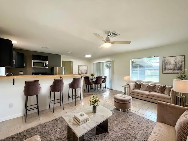 living area featuring a ceiling fan, light tile patterned flooring, and baseboards