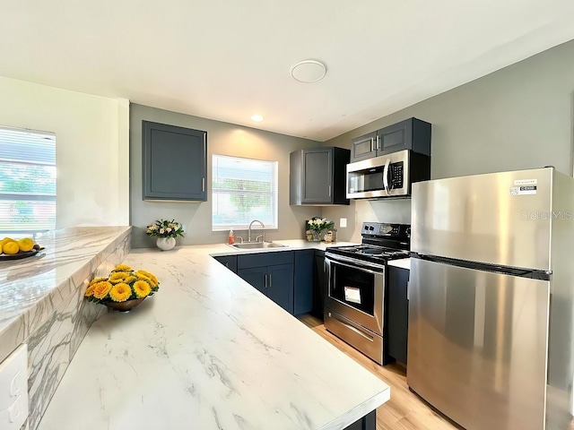 kitchen with light stone counters, stainless steel appliances, and a sink