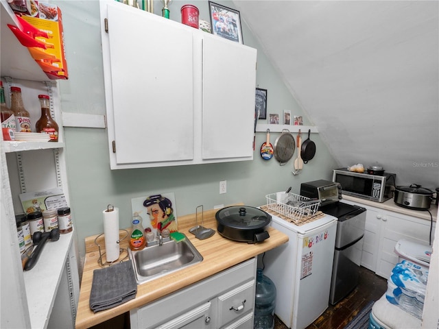 kitchen featuring lofted ceiling, sink, independent washer and dryer, and white cabinets