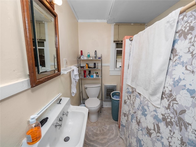 bathroom with tile patterned flooring, crown molding, heating unit, and toilet