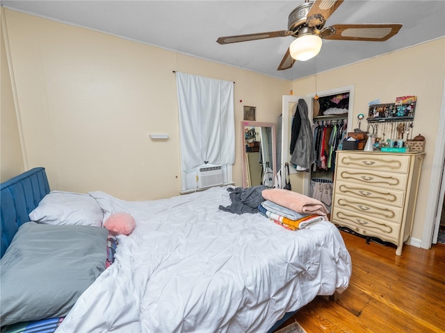 bedroom featuring hardwood / wood-style flooring, cooling unit, ceiling fan, and a closet