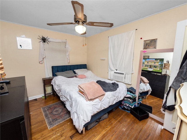 bedroom featuring cooling unit, hardwood / wood-style flooring, and ceiling fan