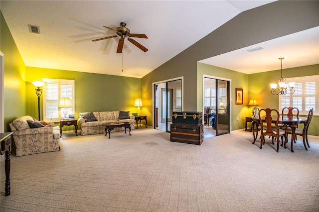 living room featuring lofted ceiling, carpet floors, plenty of natural light, and ceiling fan with notable chandelier