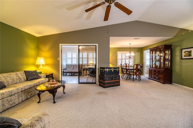 living room with ceiling fan with notable chandelier, vaulted ceiling, and light colored carpet