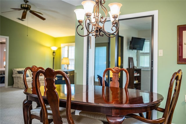 dining area with ceiling fan with notable chandelier and carpet