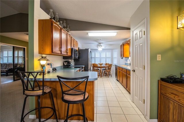 kitchen featuring ceiling fan, appliances with stainless steel finishes, lofted ceiling, and light tile patterned floors