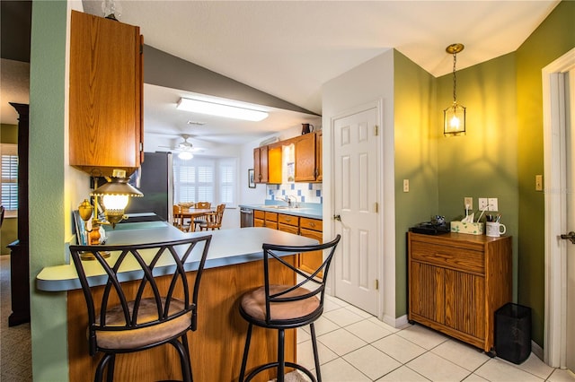 kitchen with lofted ceiling, light tile patterned floors, a breakfast bar, ceiling fan, and decorative light fixtures