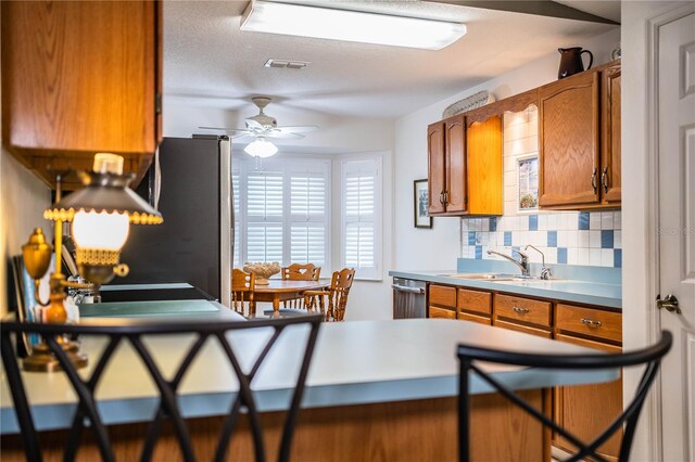 kitchen featuring tasteful backsplash, a textured ceiling, stainless steel appliances, ceiling fan, and sink