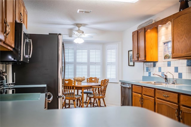 kitchen featuring a textured ceiling, stainless steel dishwasher, sink, ceiling fan, and decorative backsplash