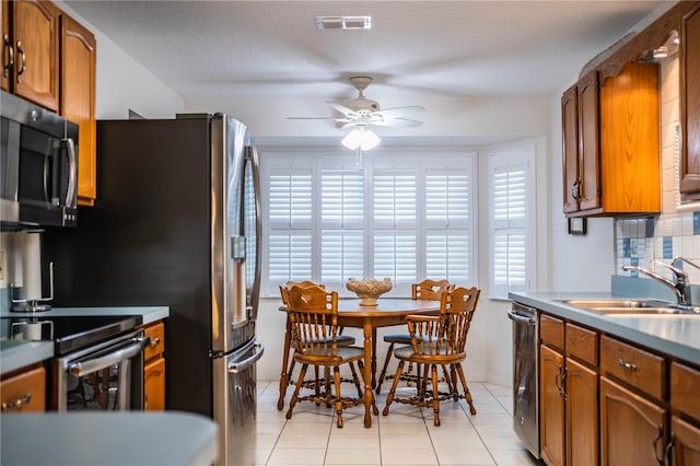 kitchen with a textured ceiling, ceiling fan, appliances with stainless steel finishes, light tile patterned flooring, and sink