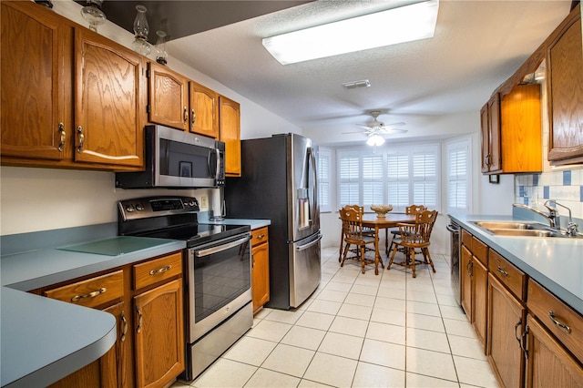 kitchen featuring ceiling fan, sink, stainless steel appliances, and light tile patterned flooring