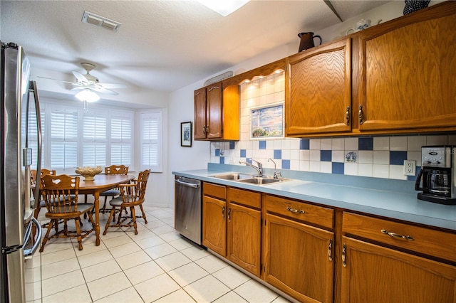 kitchen featuring decorative backsplash, appliances with stainless steel finishes, ceiling fan, sink, and light tile patterned flooring