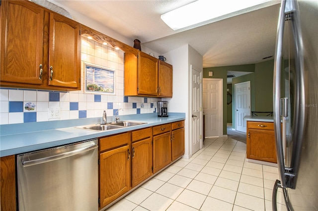 kitchen with sink, stainless steel appliances, light tile patterned floors, and decorative backsplash