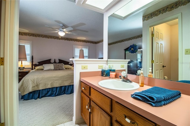 bathroom featuring ceiling fan, a skylight, vanity, and a healthy amount of sunlight