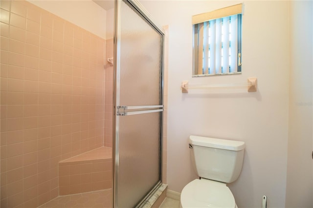 bathroom featuring a shower with door and toilet