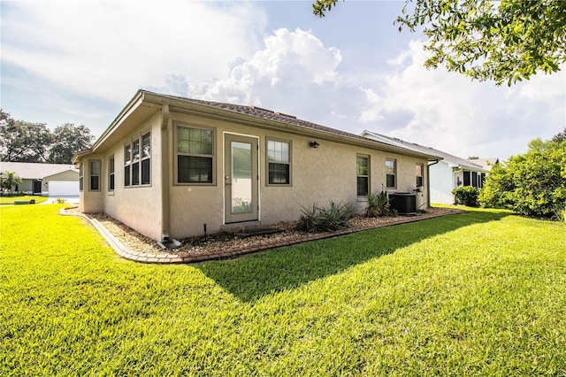 back of property with central air condition unit and a lawn